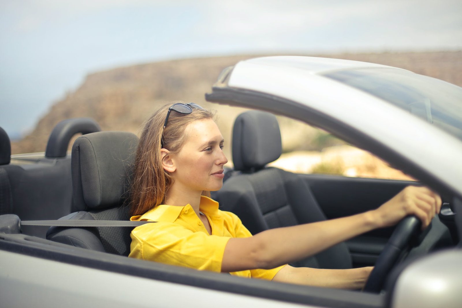 woman in yellow shirt driving a silver car